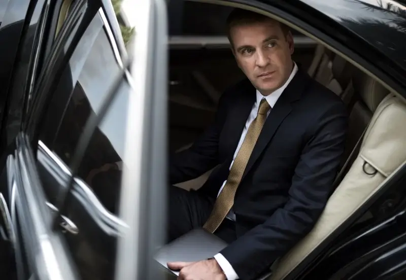 A professional businessman in a dark suit and gold tie sitting in the back of a luxury black car, illustrating the executive car service and airport transfers provided by Gateway Limousine in St. Louis and Chesterfield. A professional businessman in a dark suit and gold tie sitting in the back of a luxury black car, illustrating the executive car service and airport transfers provided by Gateway Limousine in St. Louis and Chesterfield.