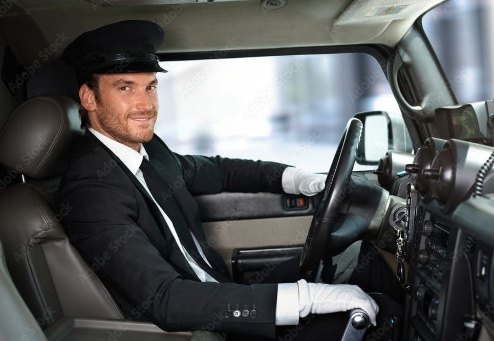 Book a St. Louis Blues Game Limo | Gateway Black Car Service 2 A professional uniformed chauffeur wearing a cap and white gloves smiling while driving a luxury vehicle, representing Gateway Limousine's premium drive-as-directed and executive car services in St. Louis.